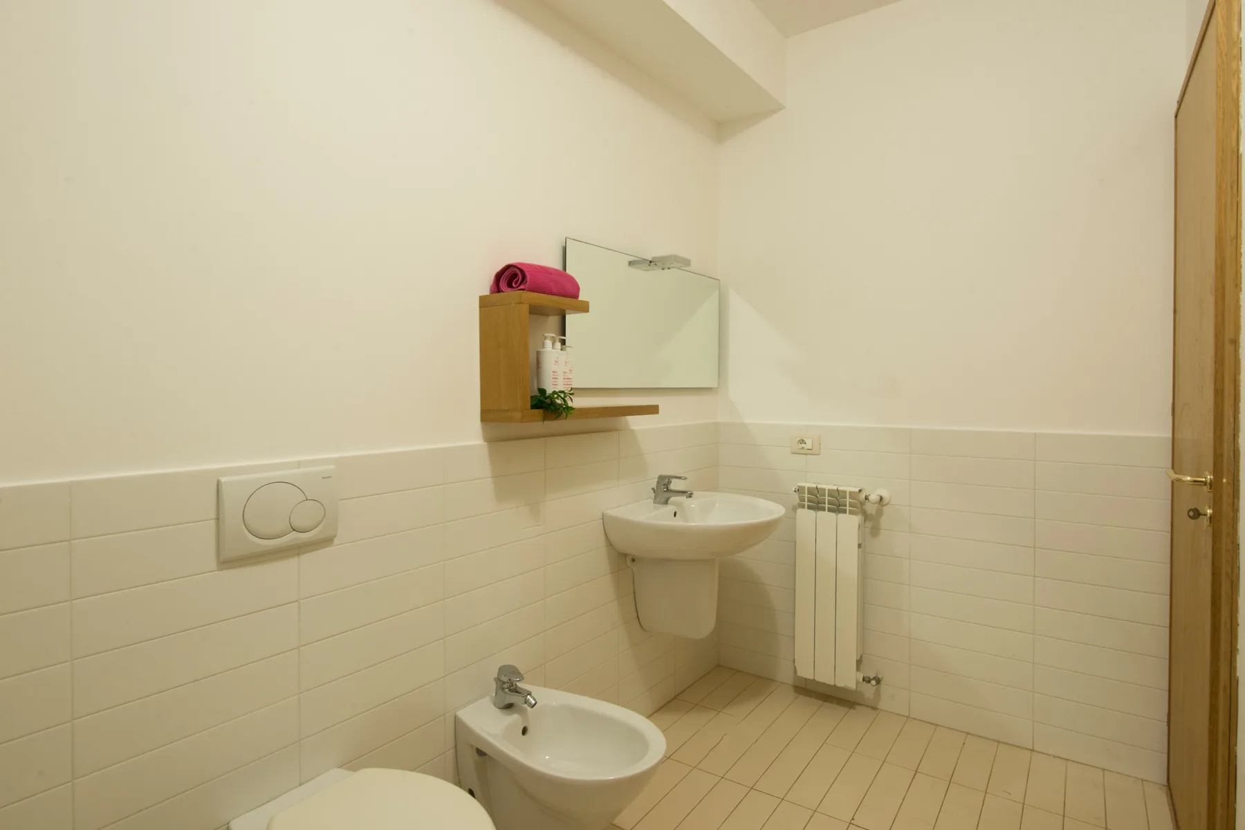 A small bathroom with a sink, mirror, and bidet.