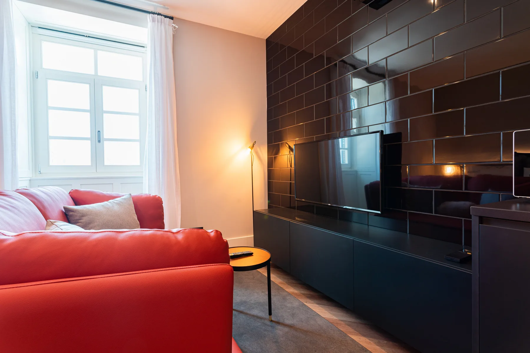 A living area with red seating, a television, and a large window.