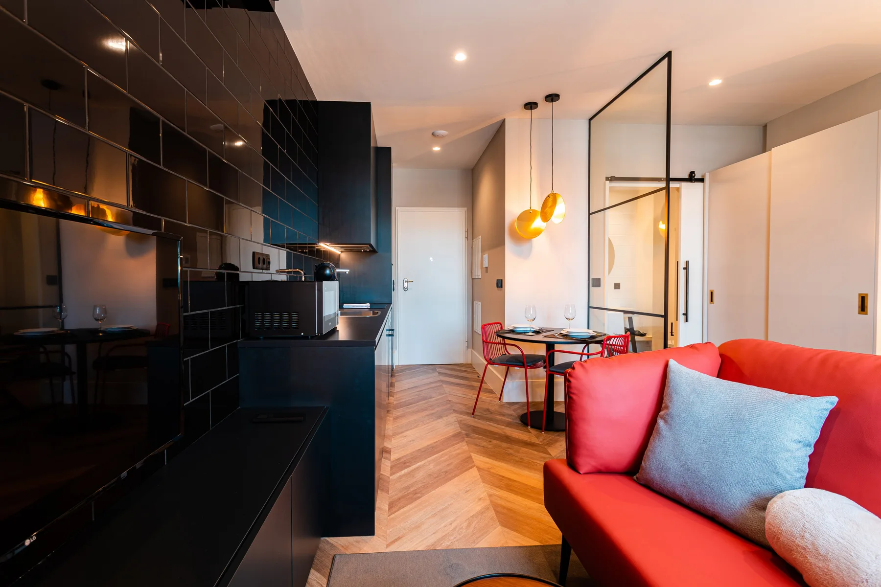 A modern studio interior with a kitchen, dining area, and red seating.