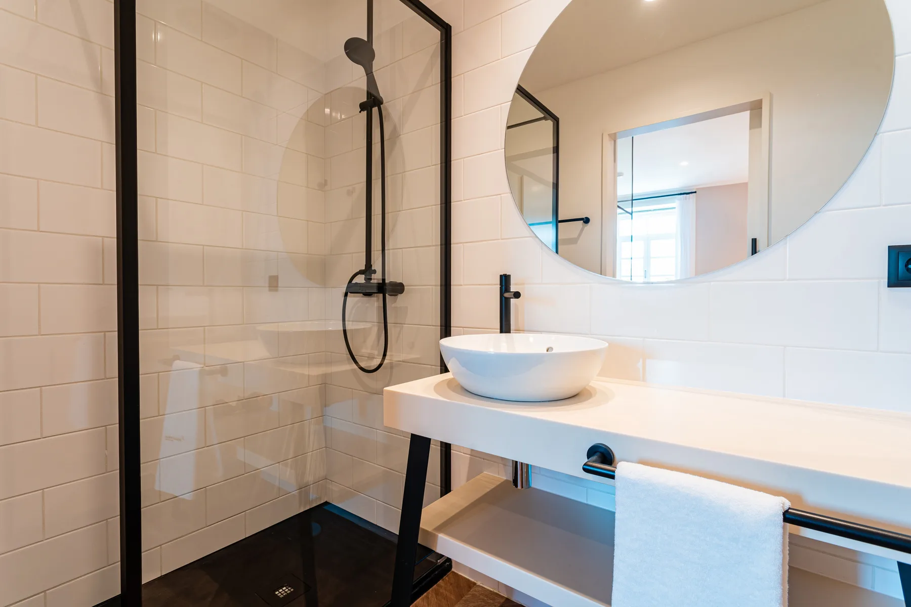 A modern bathroom with a glass shower and a white vessel sink.