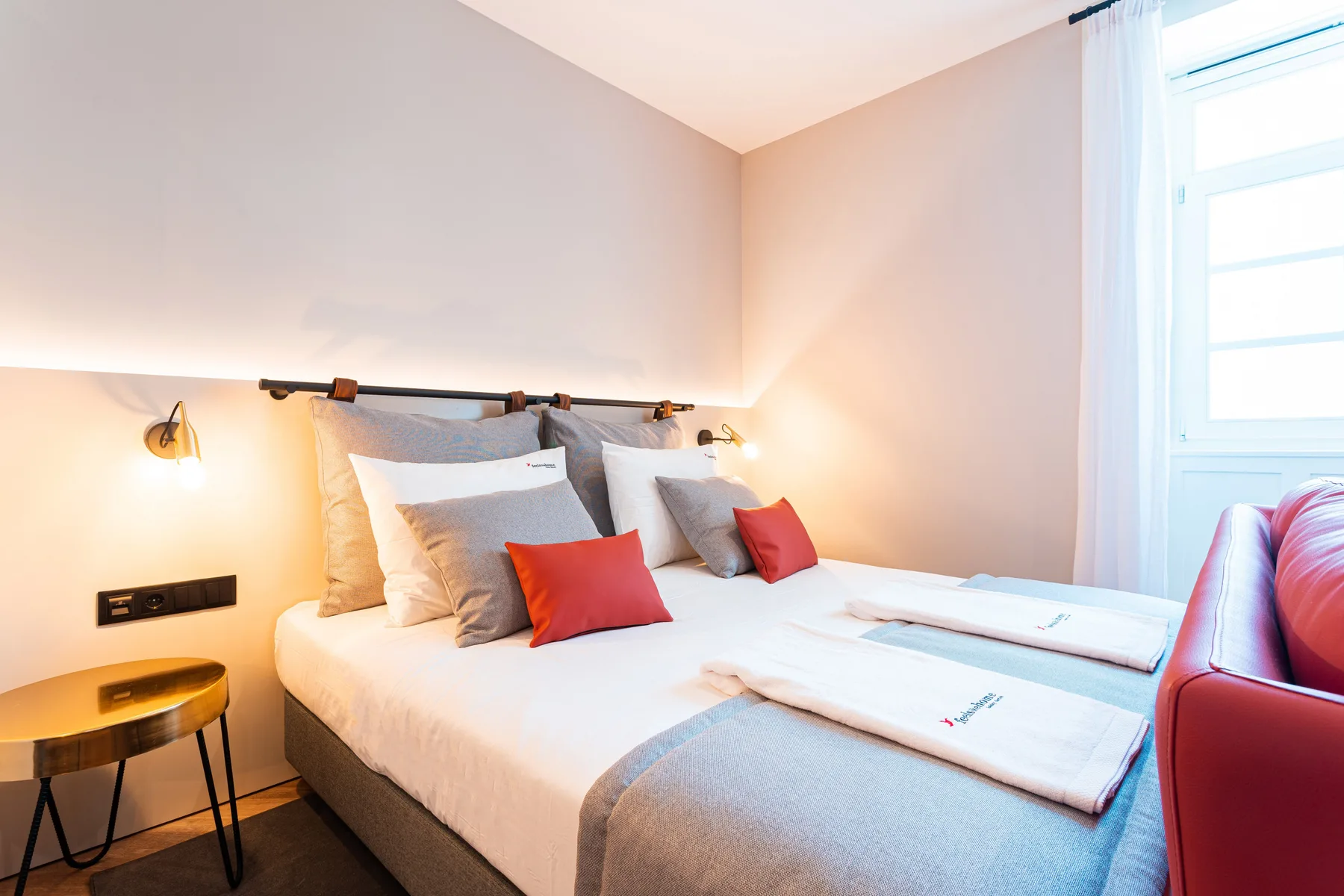 A bedroom with a neatly made bed and a bright window.