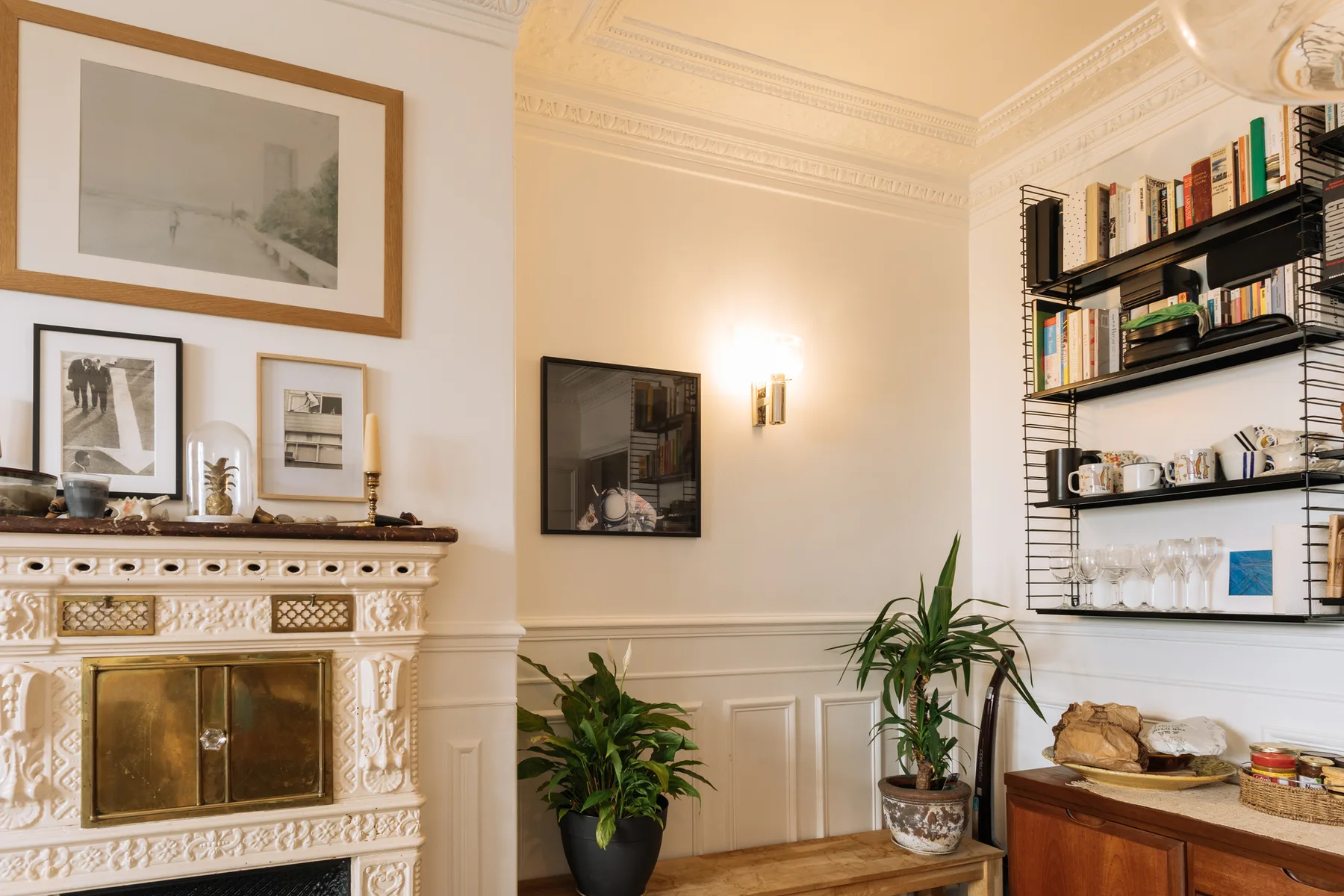 A living room with a decorative fireplace, framed pictures, and wall shelving.