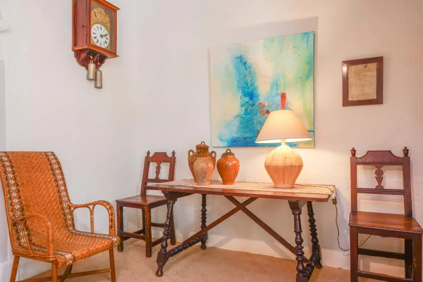 Una zona de estar con una mesa de madera, sillas y una obra de arte colorida en la pared.