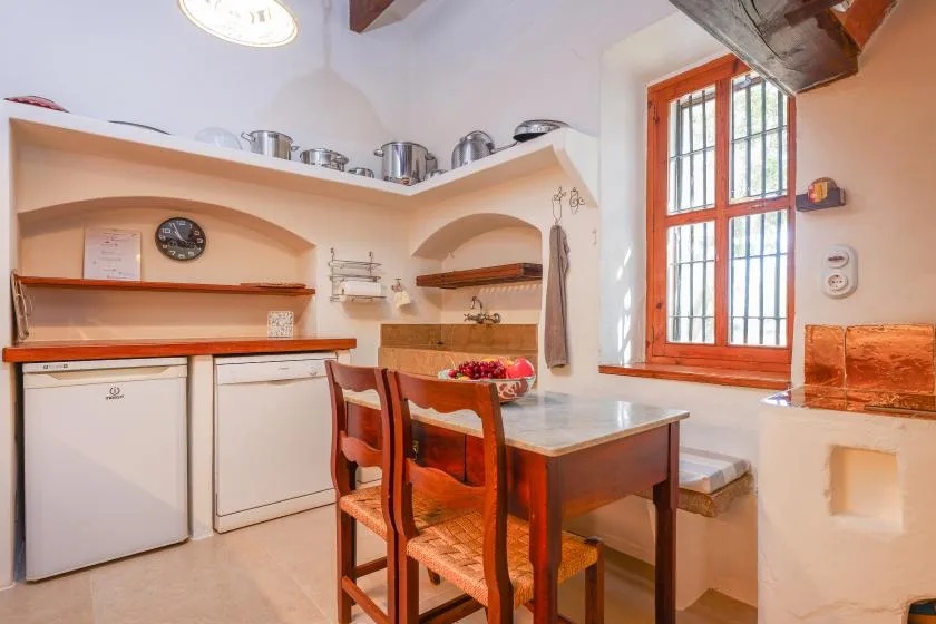 Una cocina compacta con una mesa de comedor de madera junto a una ventana con barrotes.
