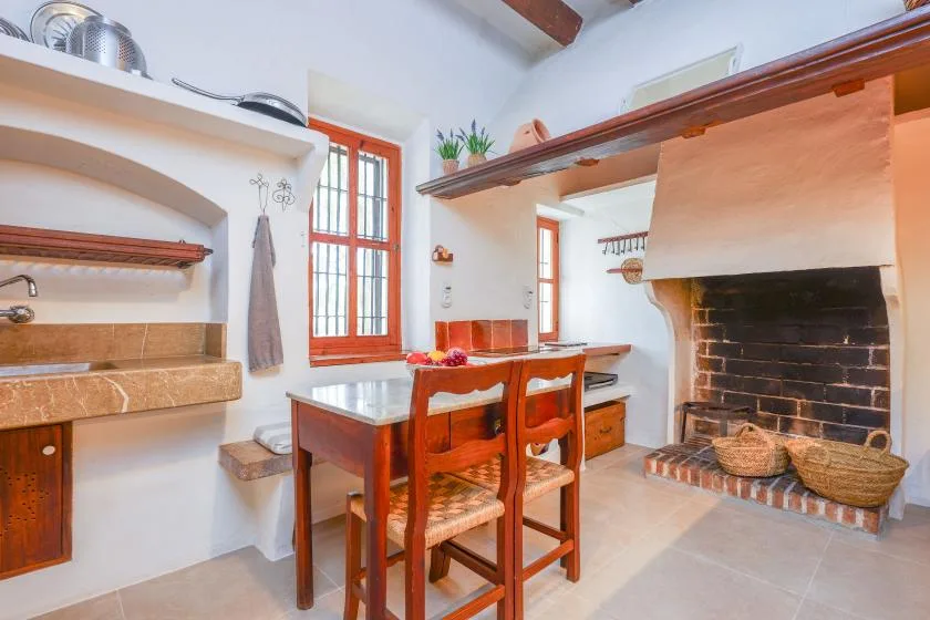 Una zona de comedor en la cocina con una mesa de madera junto a una gran chimenea de ladrillo.