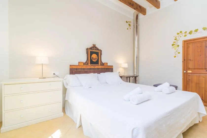 Un dormitorio con una cama grande, sábanas blancas y una cómoda.