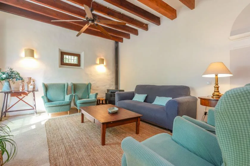 Una sala de estar con asientos alrededor de una mesa de centro de madera bajo vigas expuestas.