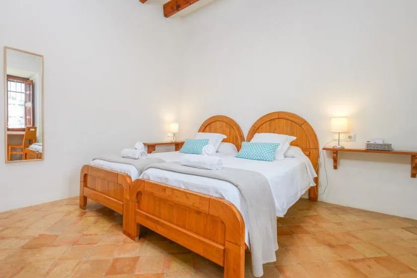 Un dormitorio con dos camas de madera, ropa de cama blanca y cojines azules.