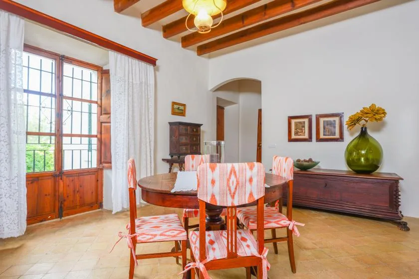 Un comedor con una mesa y sillas de madera bajo vigas de techo expuestas.