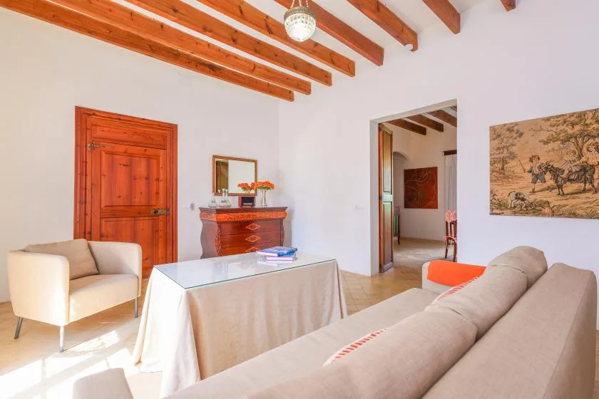 Una sala luminosa con asientos, una mesa con tapa de vidrio y vigas de madera a la vista.