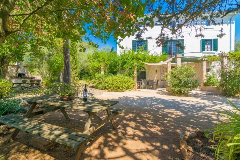 Un patio ajardinado con mesas de picnic está frente a un edificio blanco.