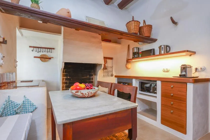 Una cocina rústica con una mesa central y un horno empotrado.
