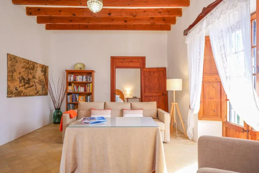 Una sala de estar con sofá, estantería y ventanas luminosas.