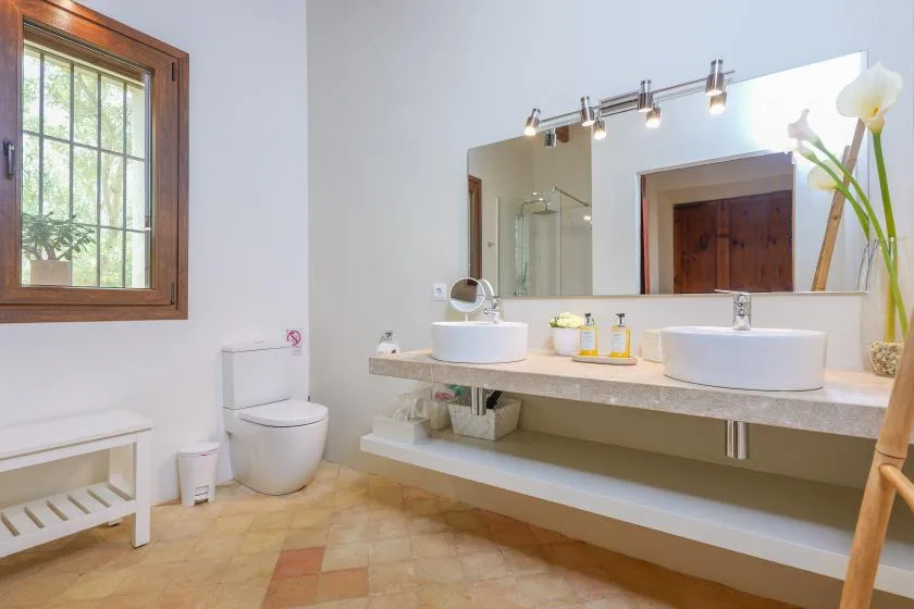Un baño luminoso con lavabo doble, espejos y una ventana.