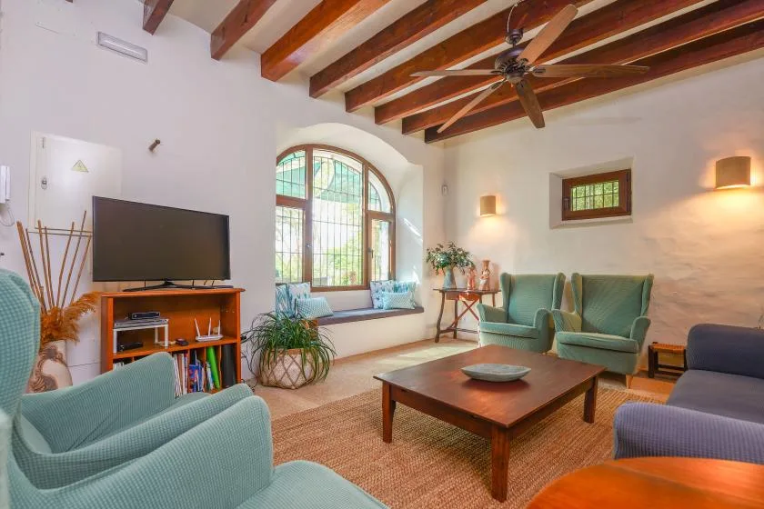 Una sala de estar con asientos alrededor de una mesa de centro de madera y una gran ventana arqueada.