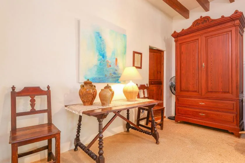 Una habitación amueblada con una mesa de madera, cerámica decorativa y un armario grande.