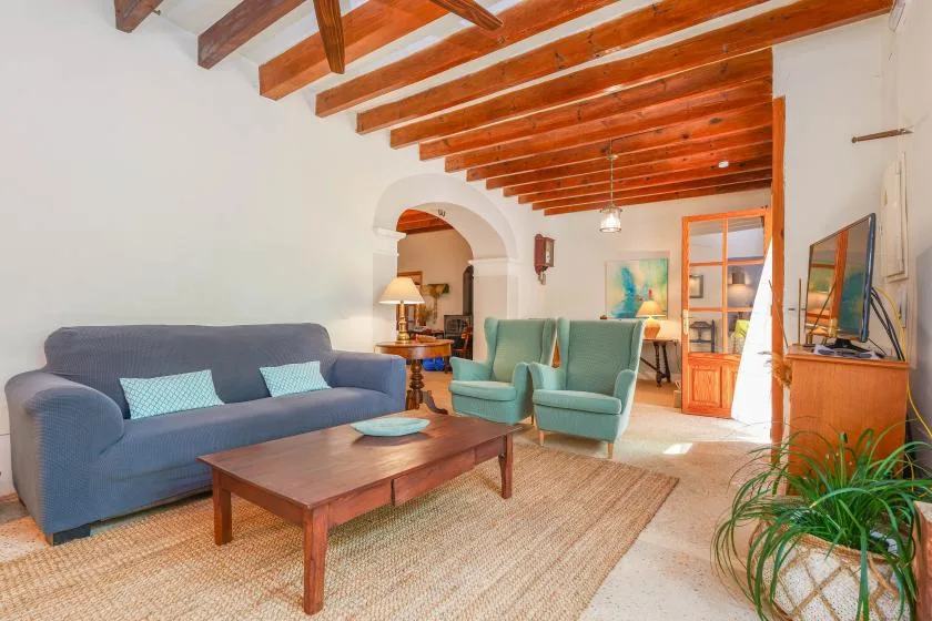 Una sala de estar con asientos azules y verdes alrededor de una mesa de centro de madera.