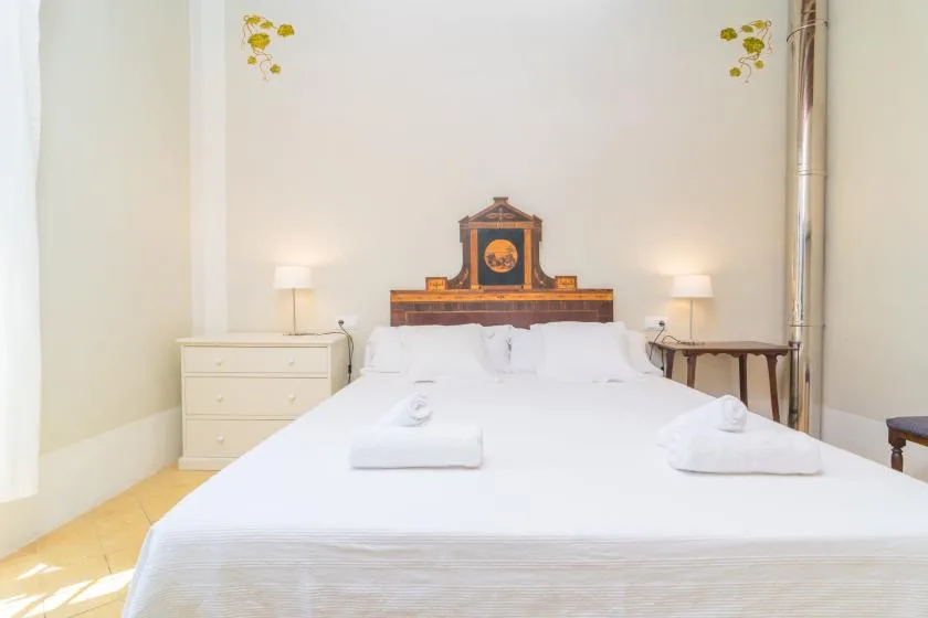 Un dormitorio con una cama bien tendida, mesitas de noche y lámparas.