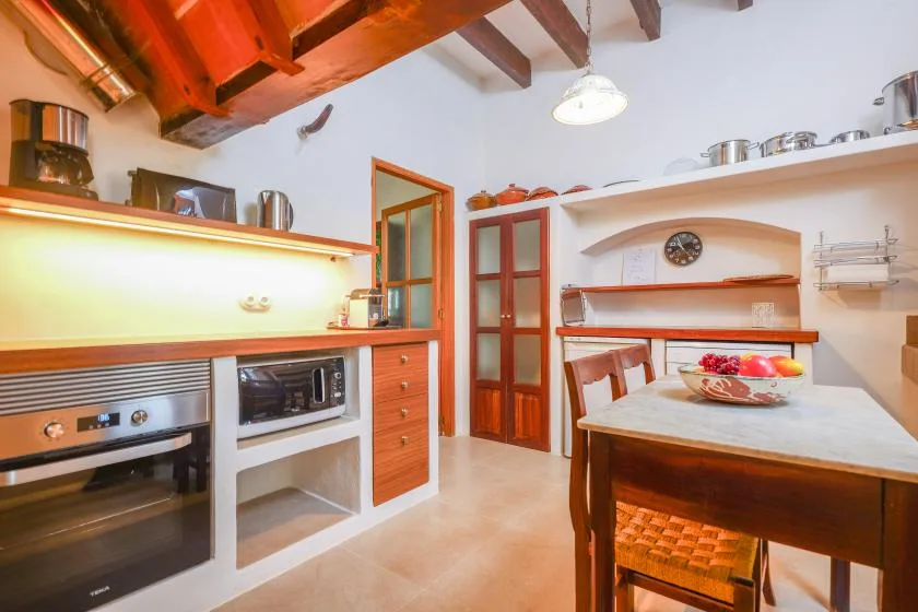 Una cocina luminosa con una mesa central y vigas de madera expuestas en el techo.