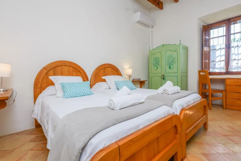 Dormitorio con dos camas, ropa de cama blanca y un armario verde.