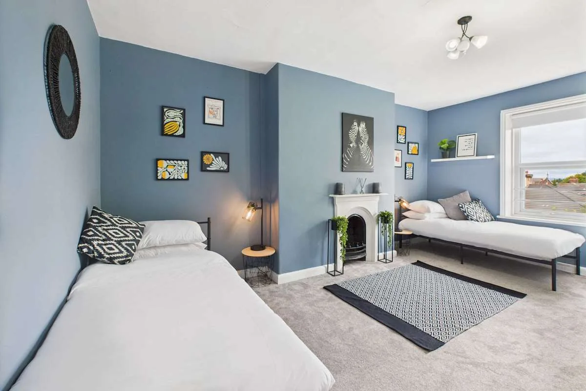 Un dormitorio azul con dos camas y una chimenea.