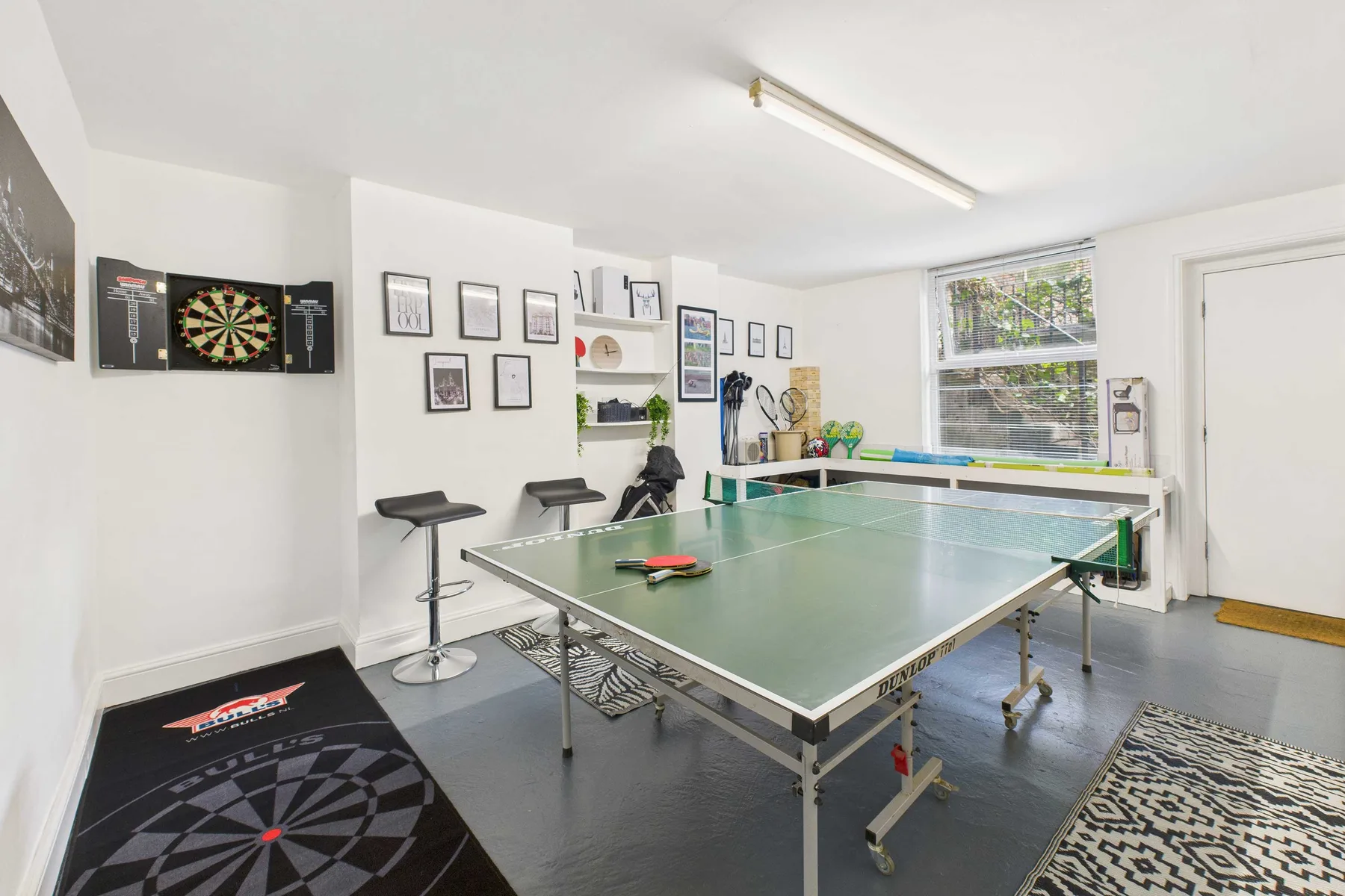 Una sala de recreación con una mesa de ping-pong y una diana.