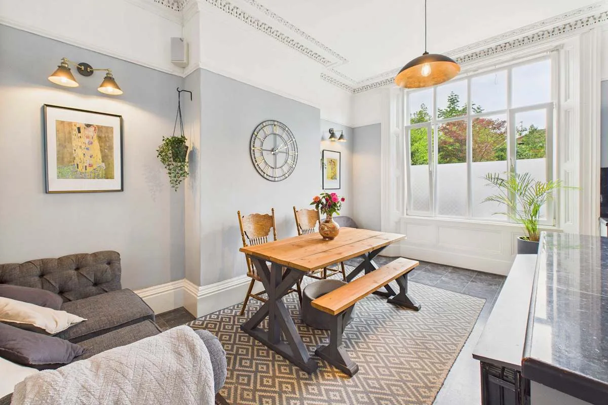 Un comedor luminoso con una mesa de madera junto a grandes ventanas.