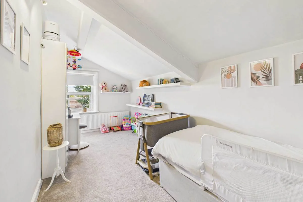 Un dormitorio infantil luminoso con una cama, un escritorio y juguetes.