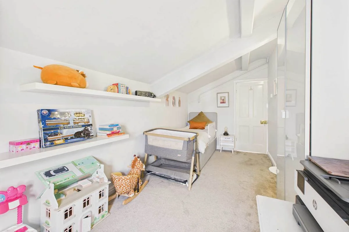 Un dormitorio infantil luminoso con una cuna y juguetes en estantes.
