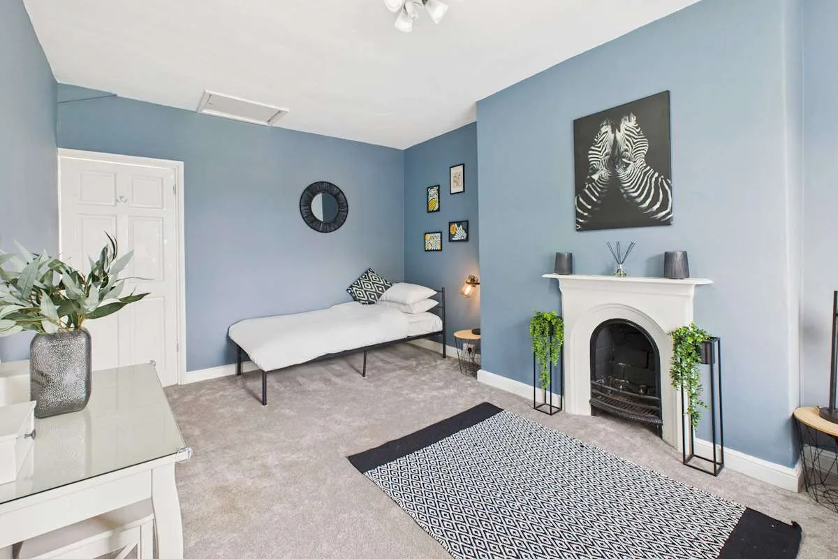 Una sala azul con un diván, una chimenea y una alfombra estampada.