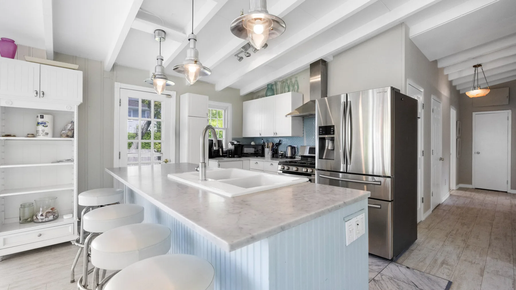 Una cocina luminosa con una isla grande y electrodomésticos de acero inoxidable.