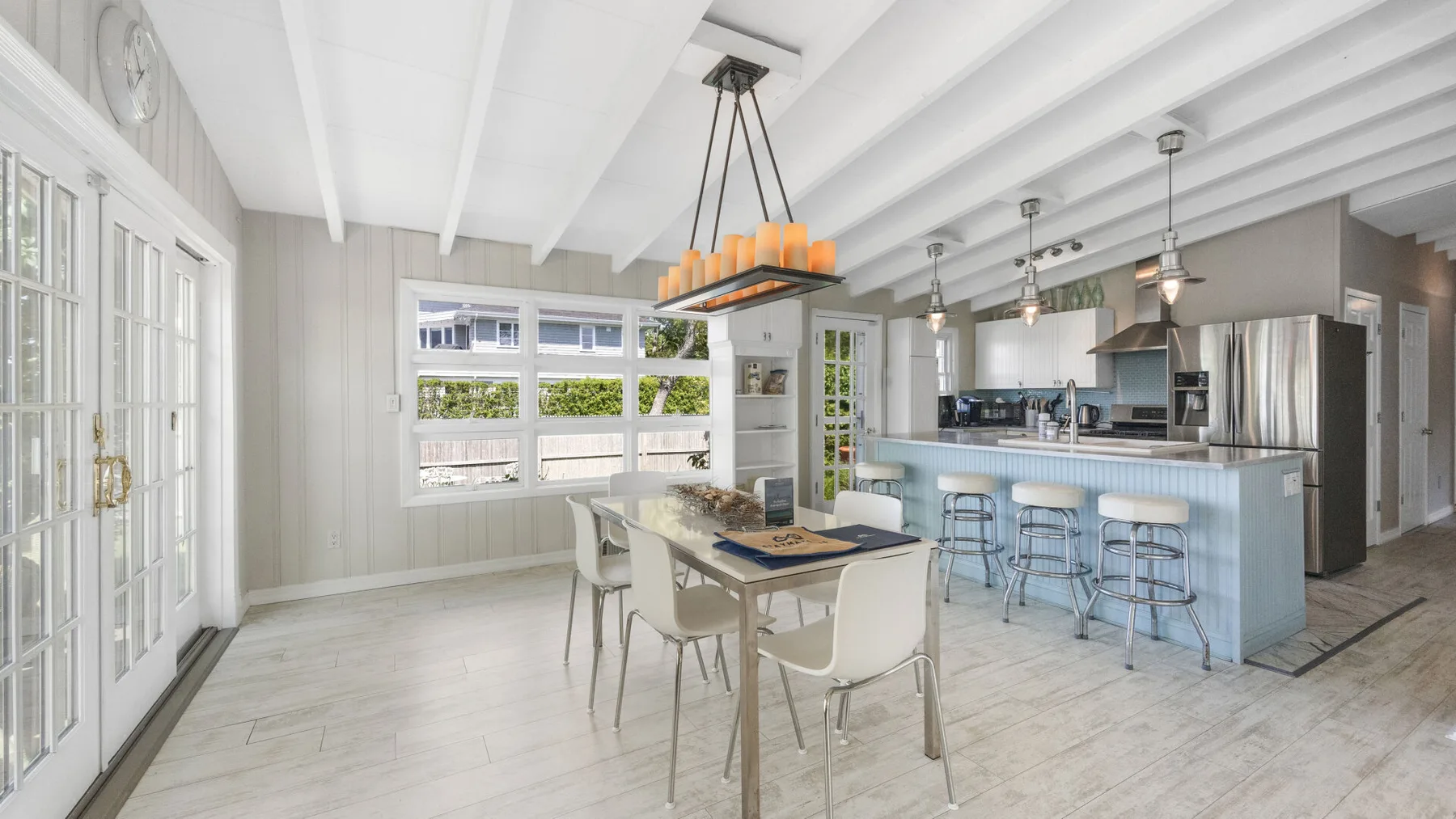 Una cocina y comedor diáfanos y luminosos, con una isla larga y una mesa de comedor.