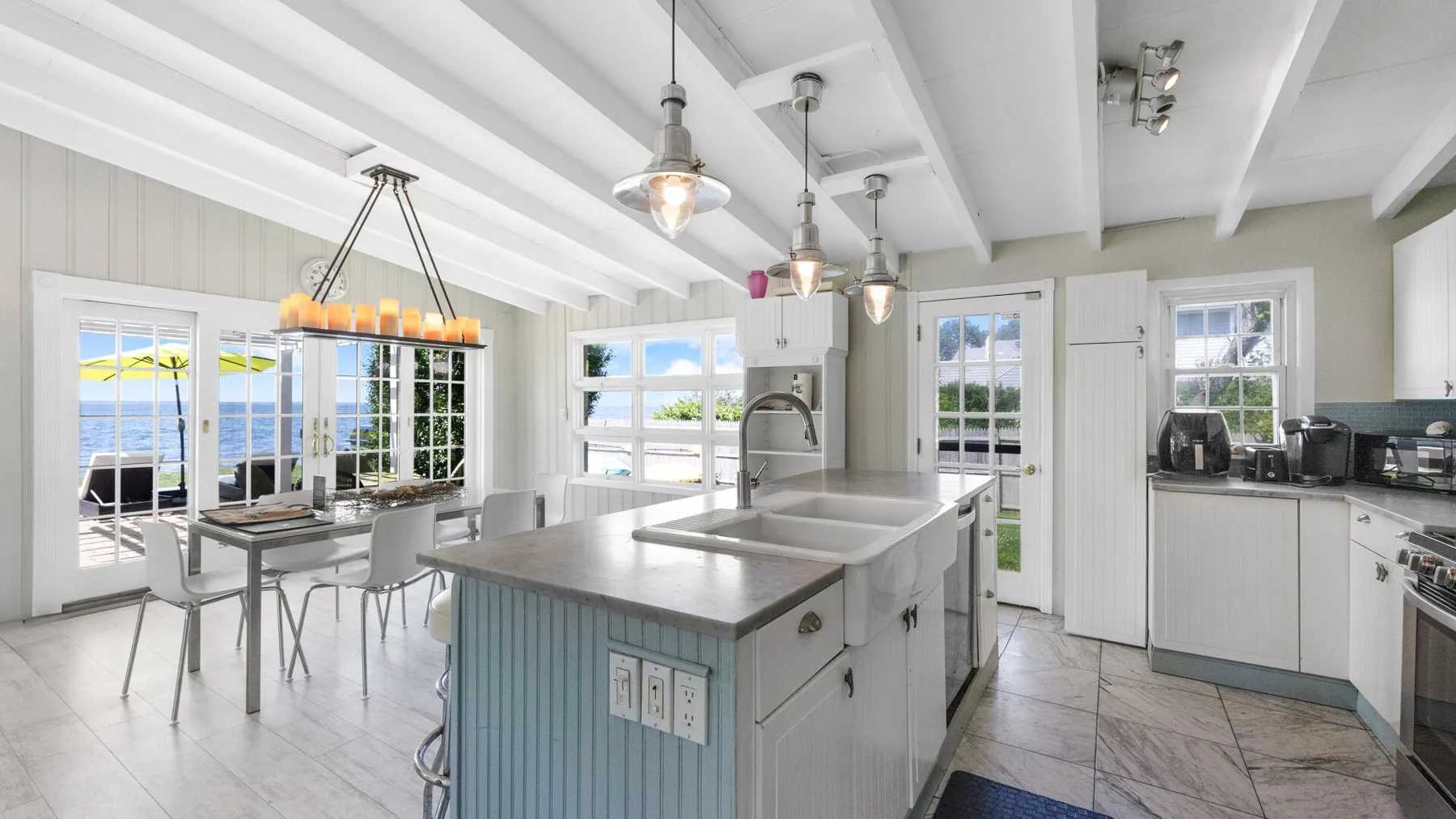 Una cocina luminosa con una isla central, una mesa de comedor y ventanales.