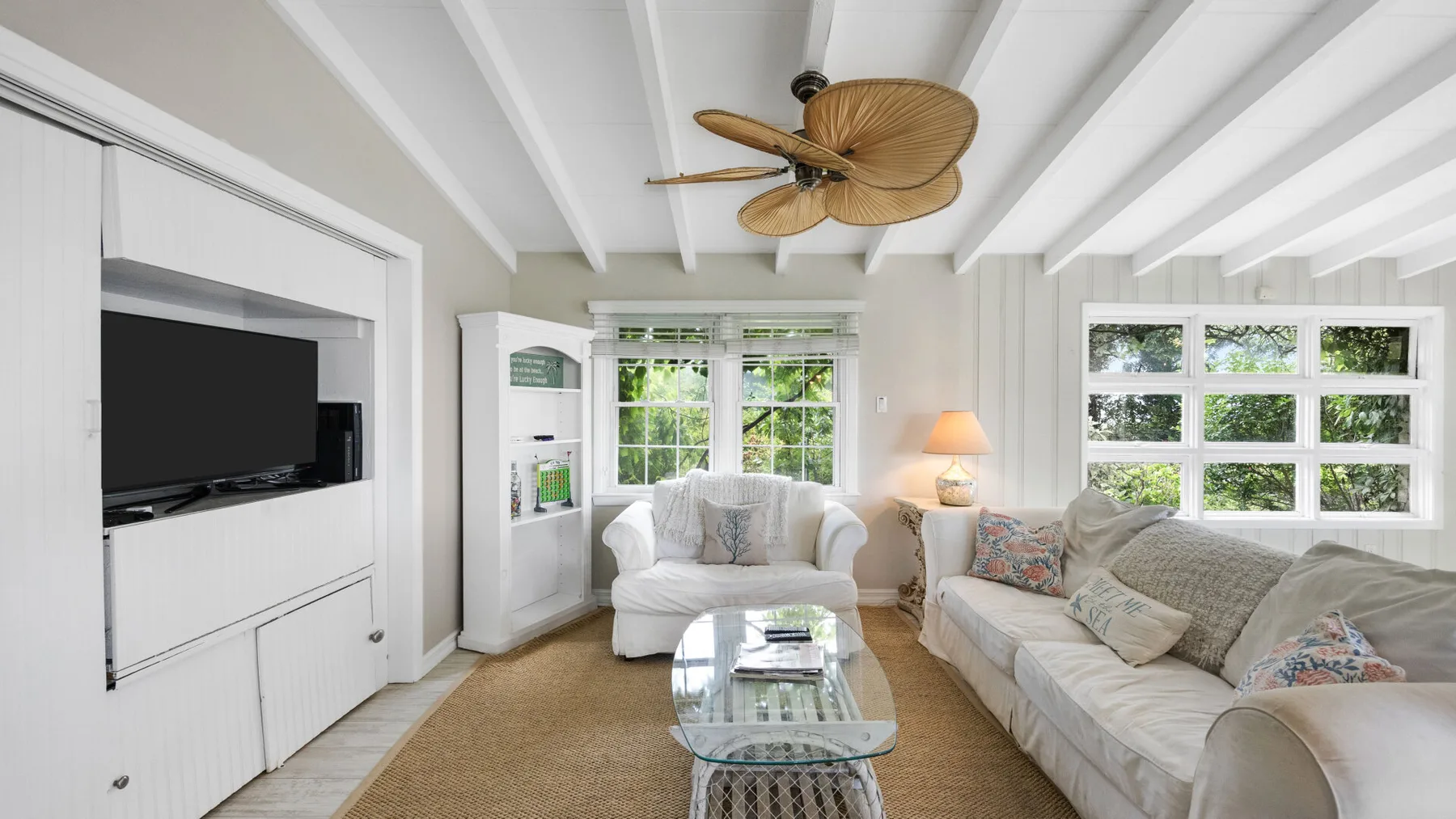 Una sala luminosa con asientos blancos, ventanas amplias y una mesa de centro de vidrio.