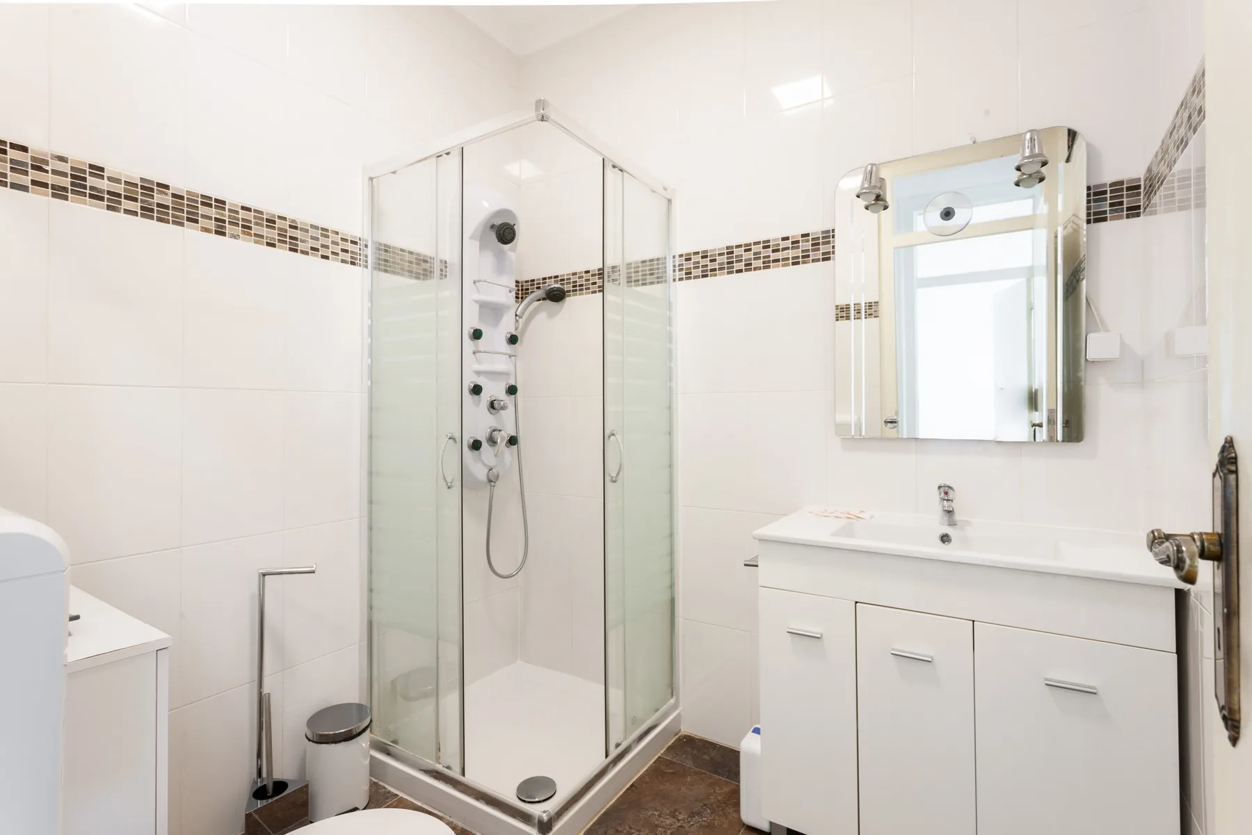 A bright bathroom with a glass shower and white vanity.