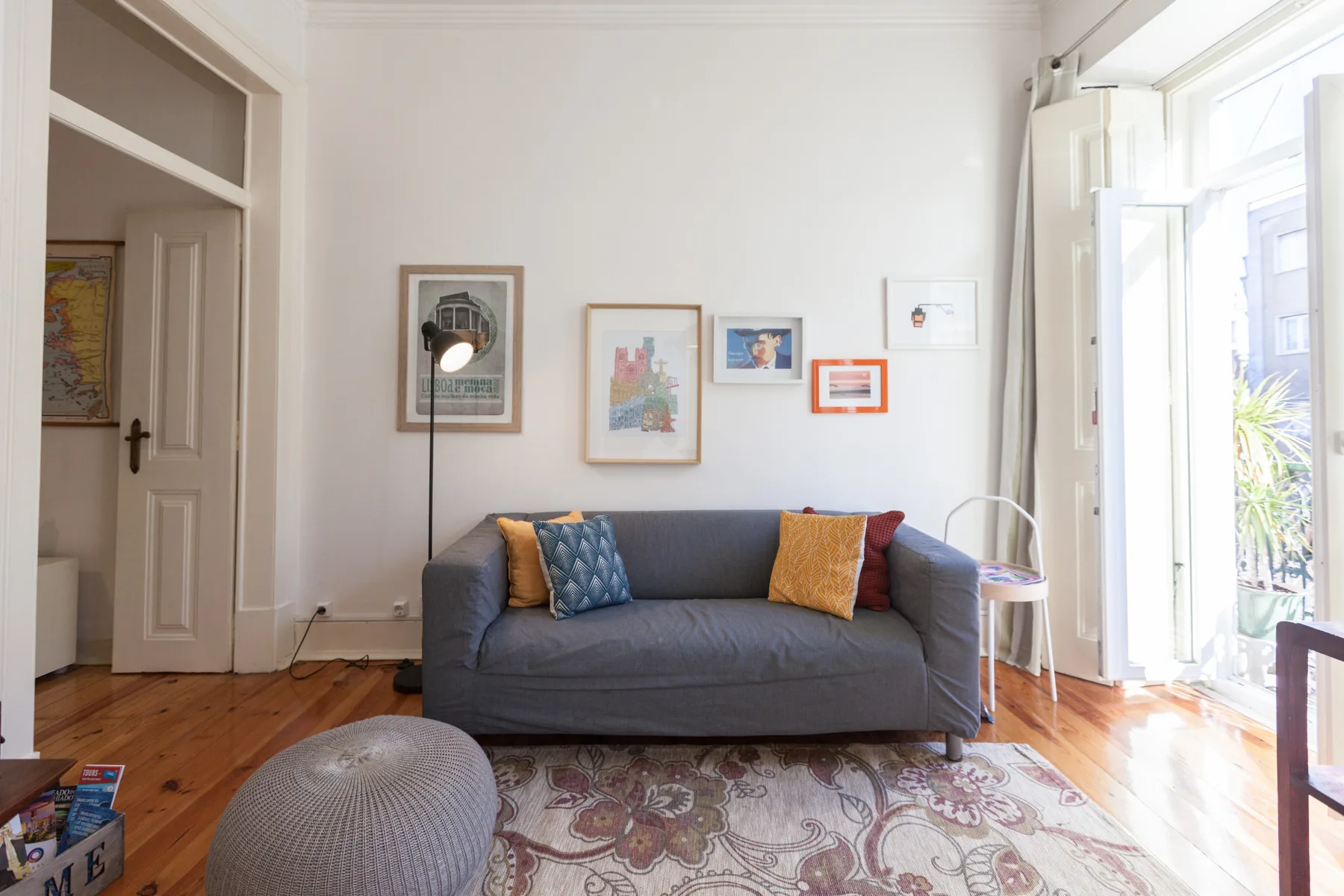A bright living room with a gray sofa and framed artwork on the wall.