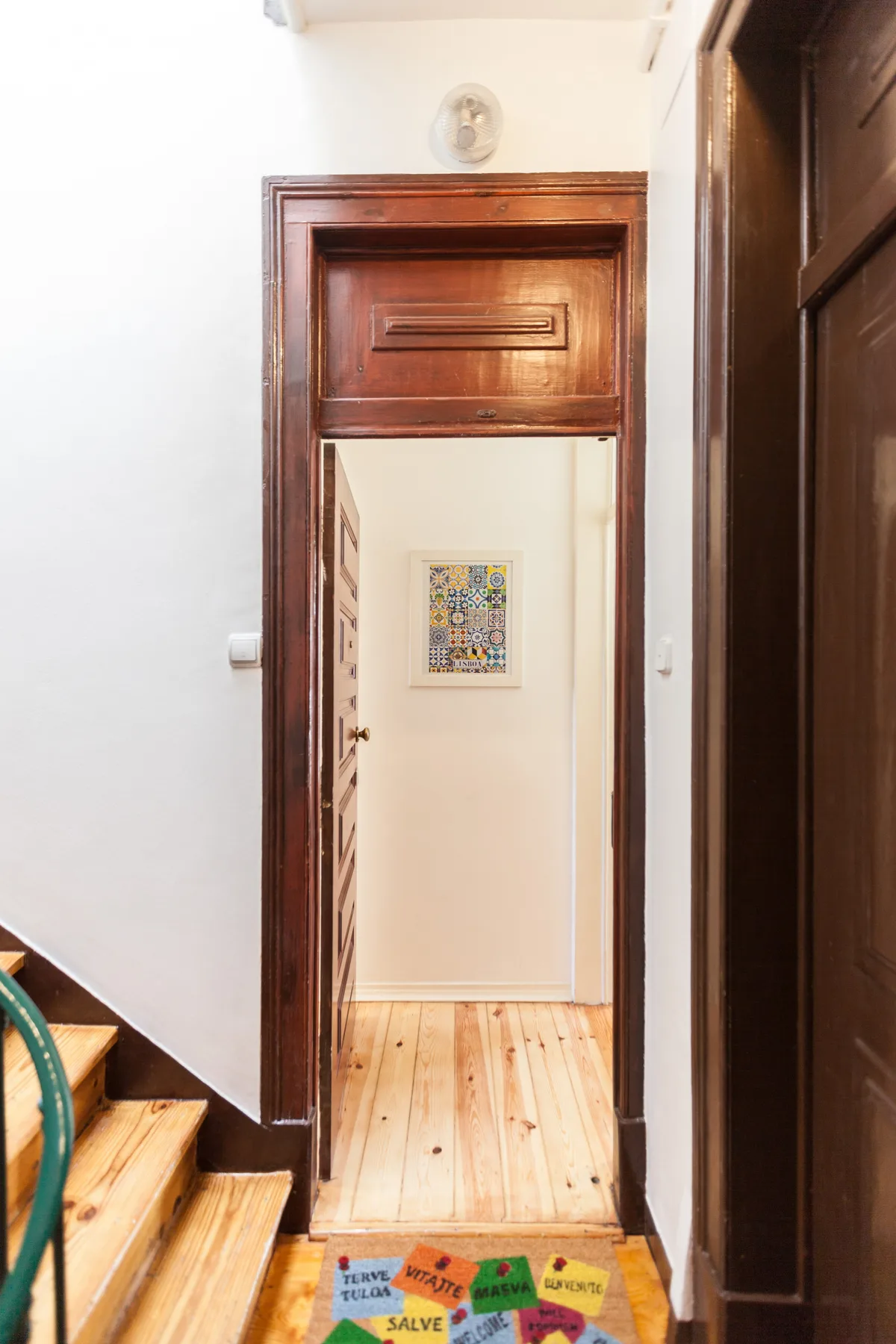 A narrow interior hallway with wooden flooring and a framed picture on the wall.