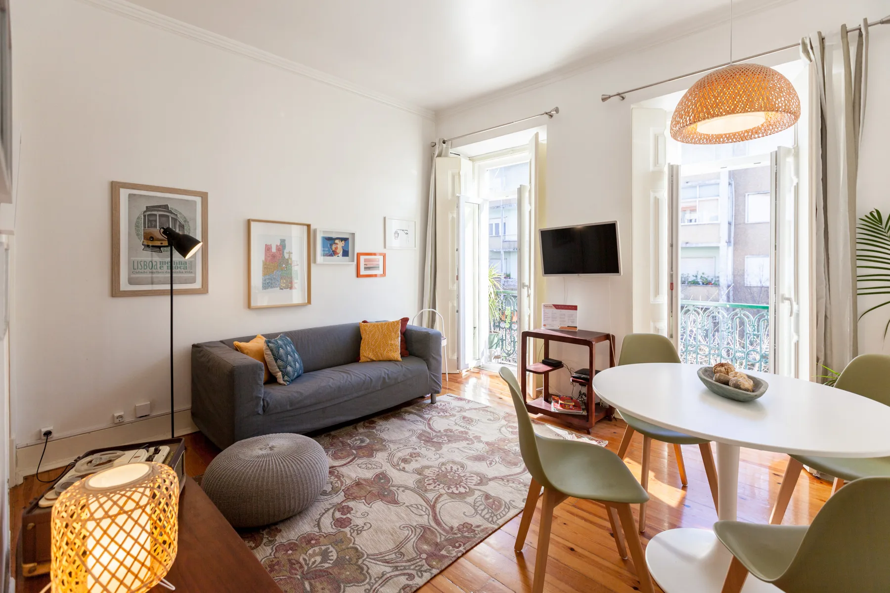 A bright living and dining area with a sofa, table, and tall windows.