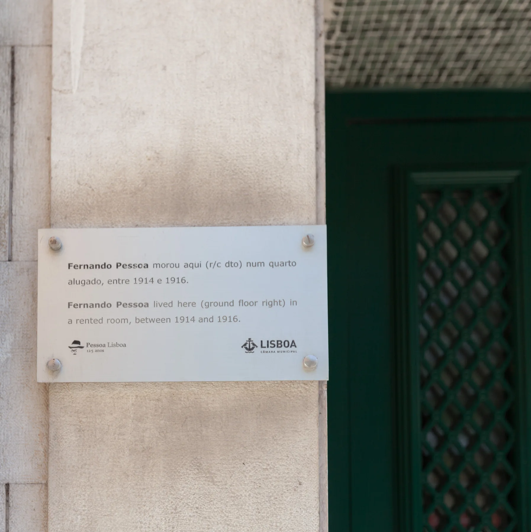 A plaque beside a dark green doorway marks a historic rented room.