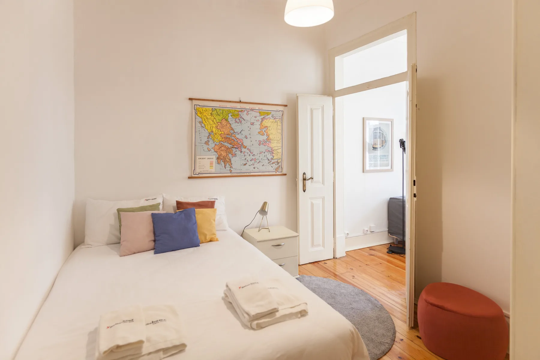 A bedroom with a bed, a wall map, and an open doorway.