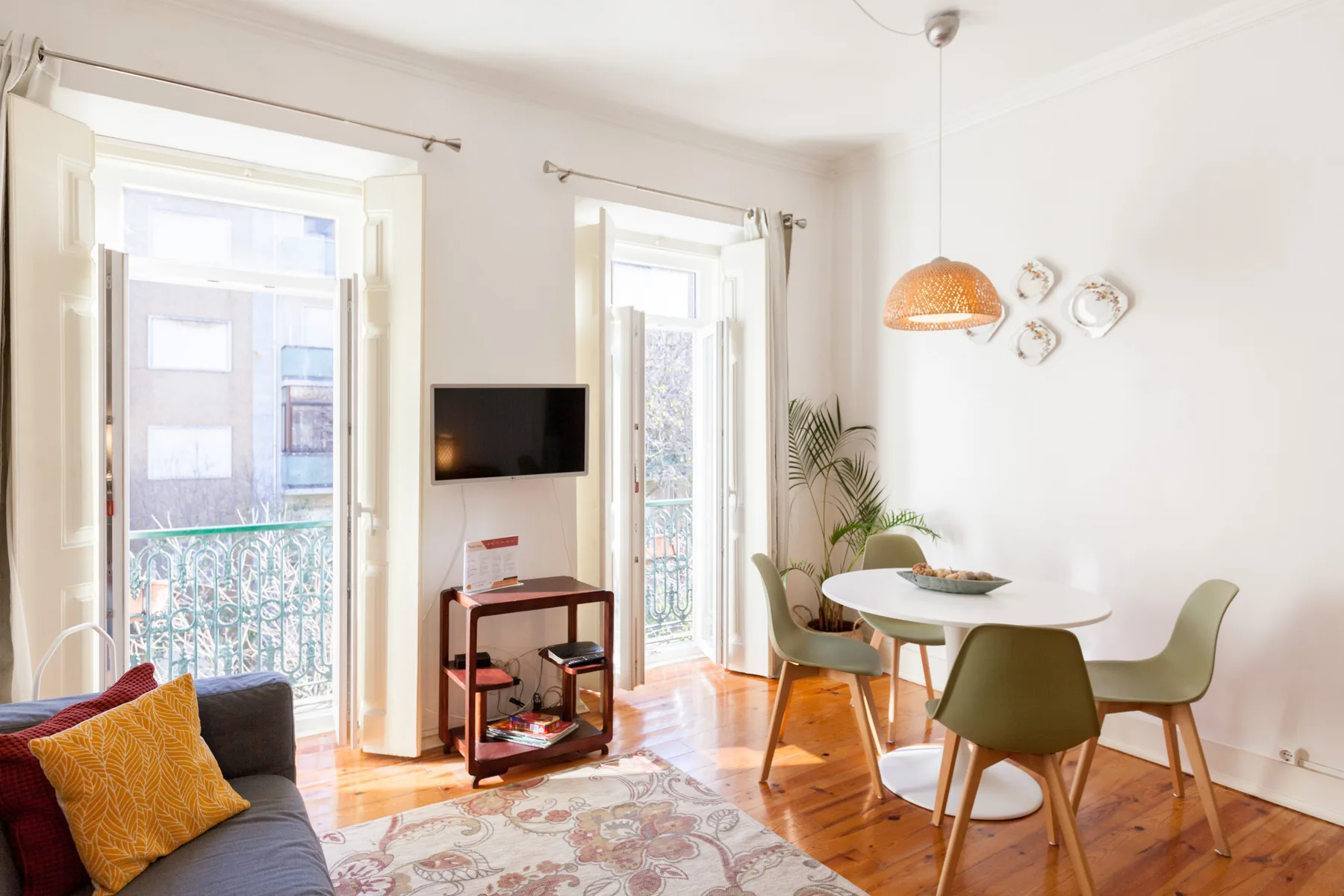 A bright living and dining area with seating, a television, and tall windows.