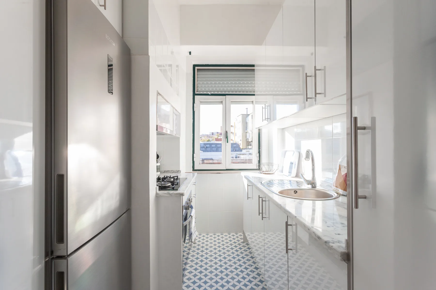 A bright kitchen with white cabinets and a patterned tile floor.