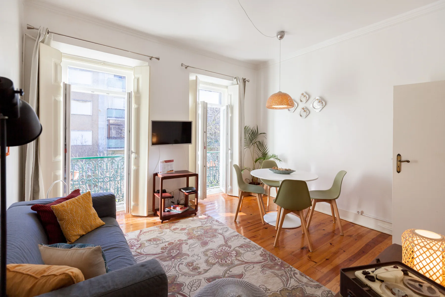 A bright living and dining area with seating, a table, and tall windows.