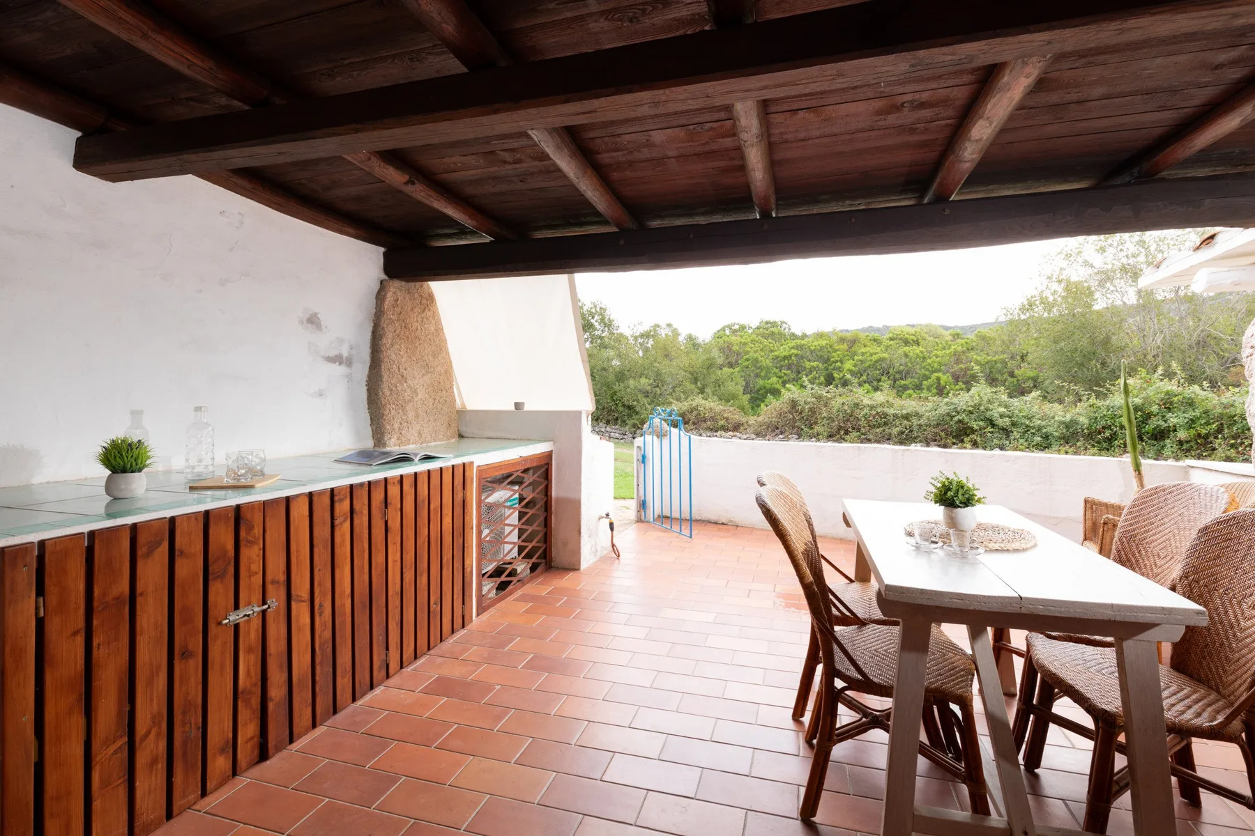 Una zona cubierta para comer al aire libre, con una mesa junto a un mostrador de madera.