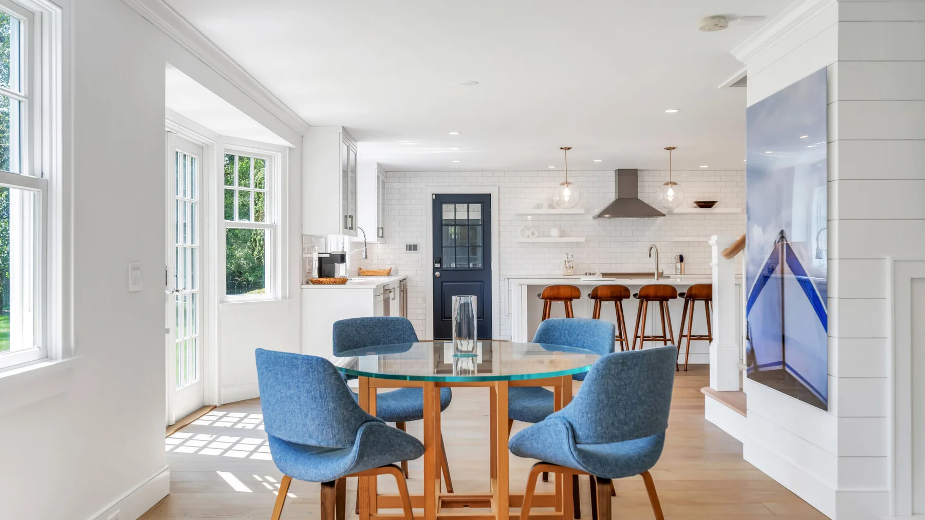 A bright dining area with a glass table and blue upholstered seating.
