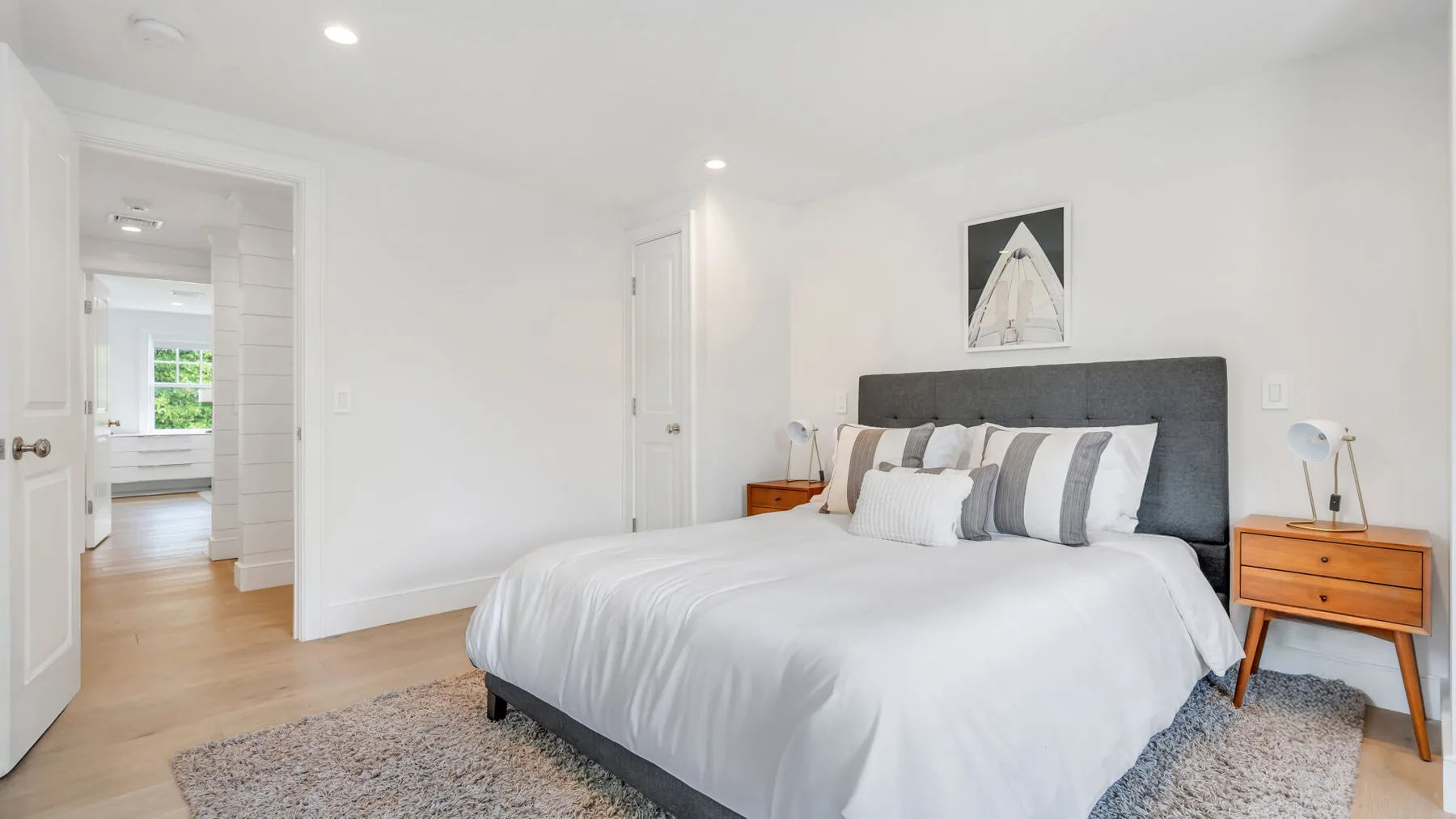 A bright bedroom with a neatly made bed and a bedside table.