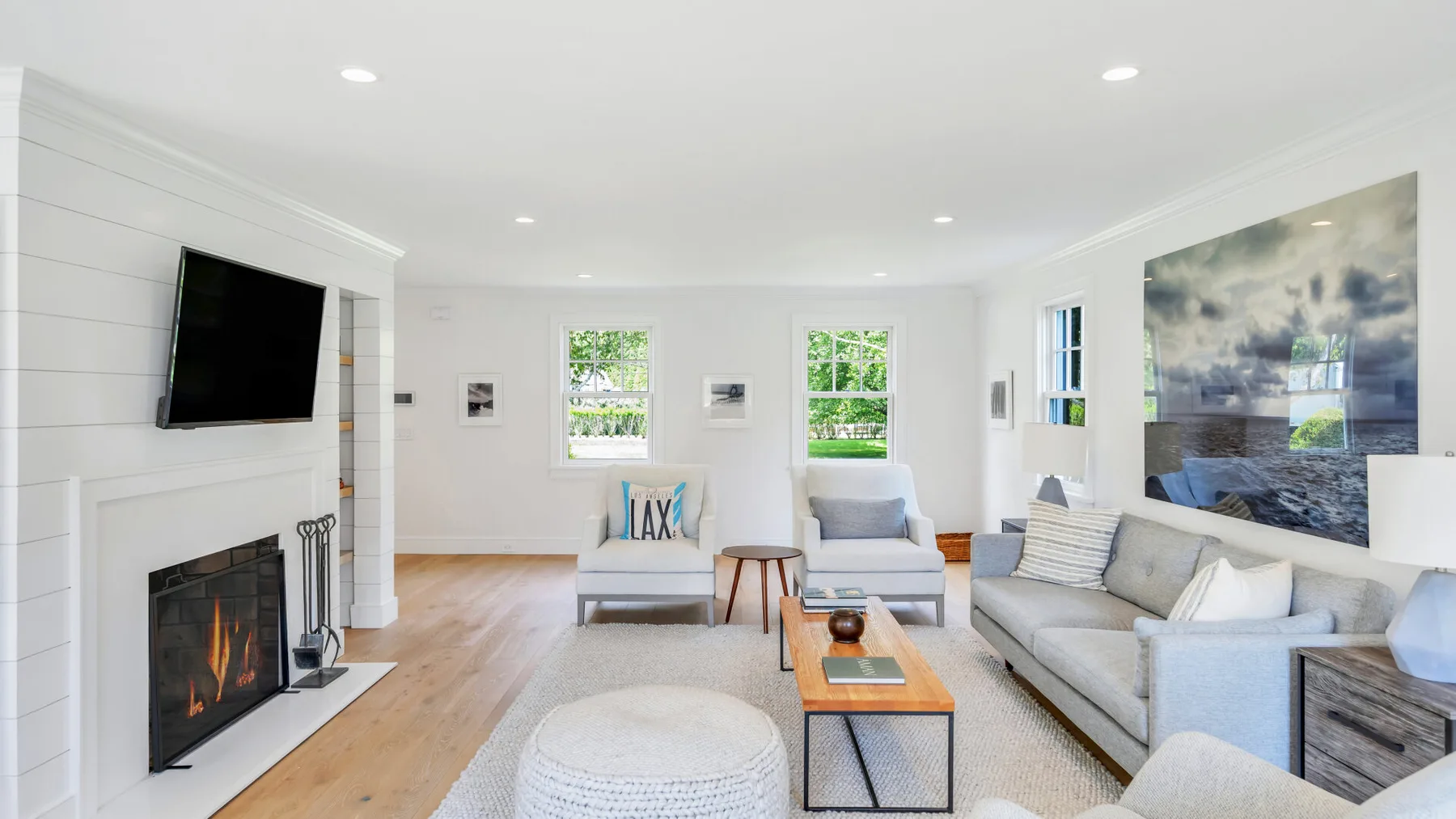 A bright living room with a fireplace, wall-mounted television, and seating.