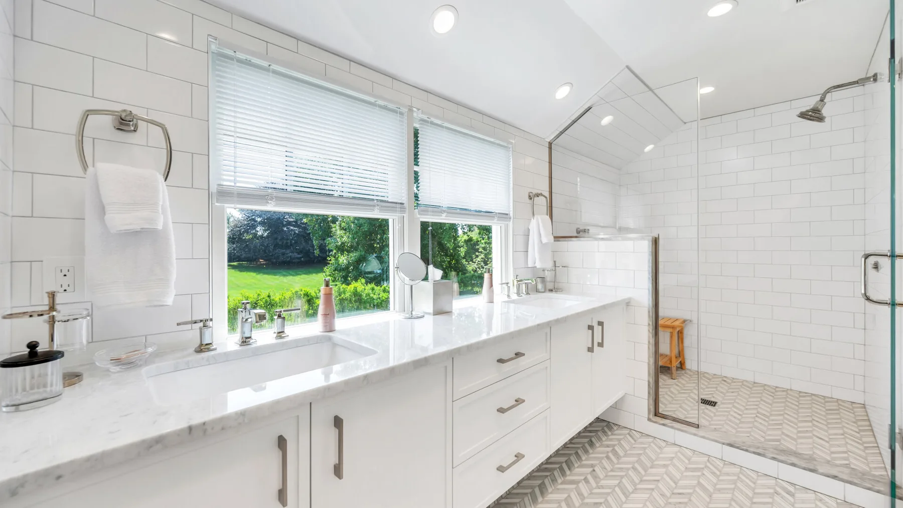 A bright bathroom with a long vanity and a glass-enclosed shower.