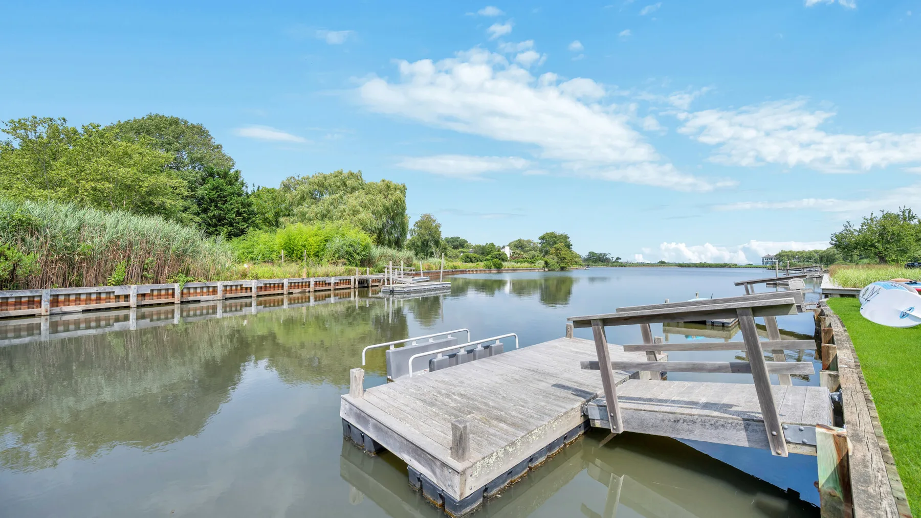Un muelle de madera se extiende sobre aguas tranquilas junto a una orilla arbolada.