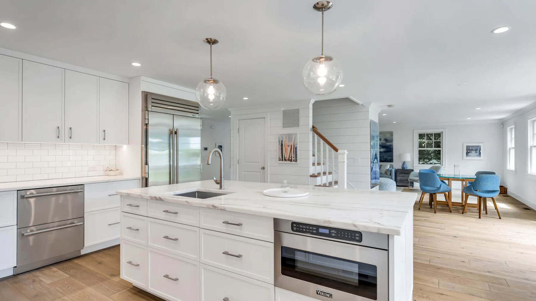 A bright kitchen with a large island, pendant lights, and an open dining area.